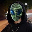 Green and silver alien mask worn with a black hood