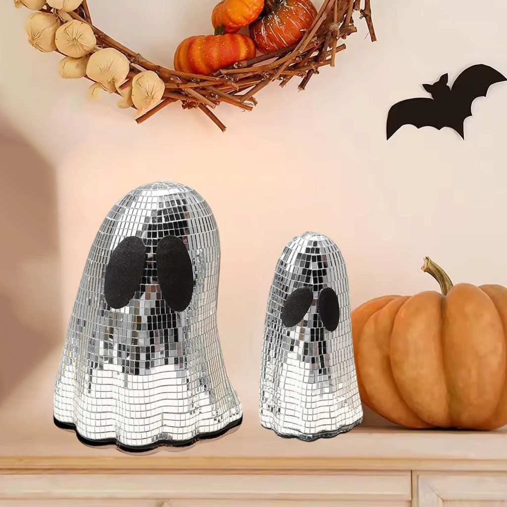 Mirrored ghost ornaments beside Halloween pumpkins on a shelf