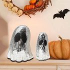 Mirrored ghost ornaments beside Halloween pumpkins on a shelf