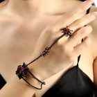 Black spider ring-linked cuff across the back of a hand