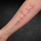ECG cross tattoo shown along forearm