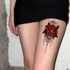 Red rose ornamental tattoo on upper leg