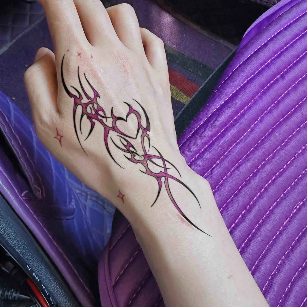 Pink thorn heart tattoo across hand and wrist