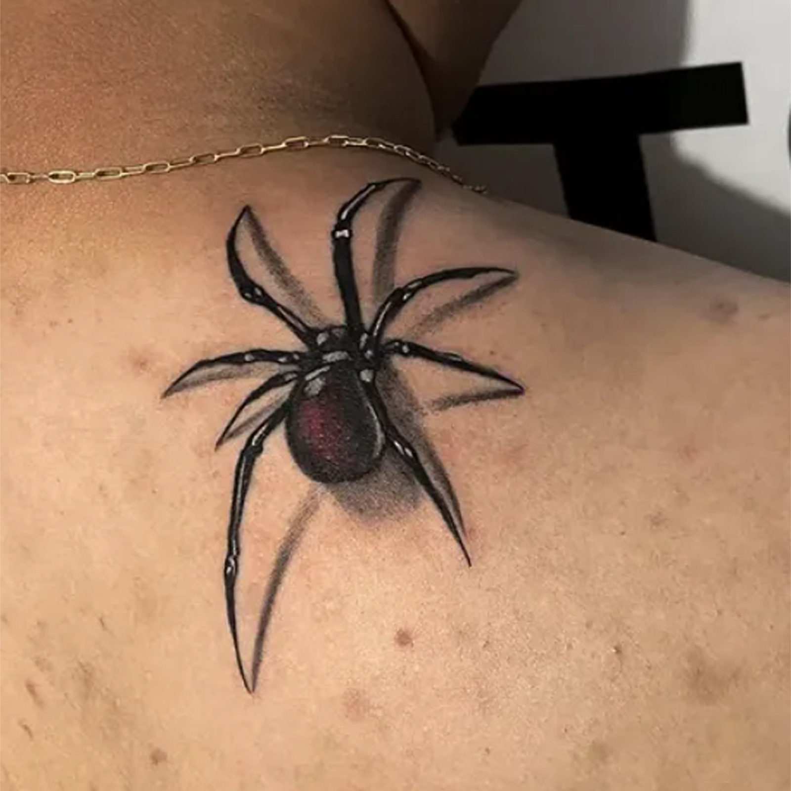 Black spider tattoo shown at shoulder
