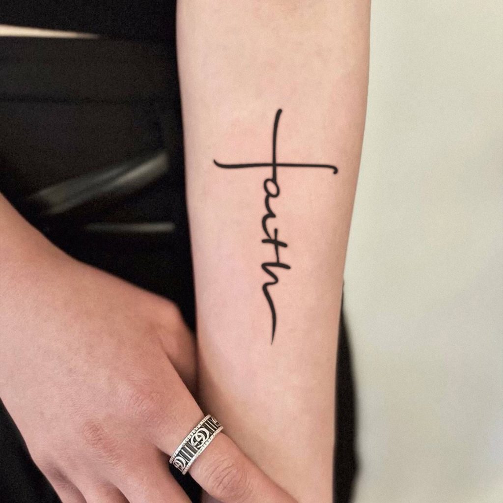 Faith script cross tattoo shown on forearm