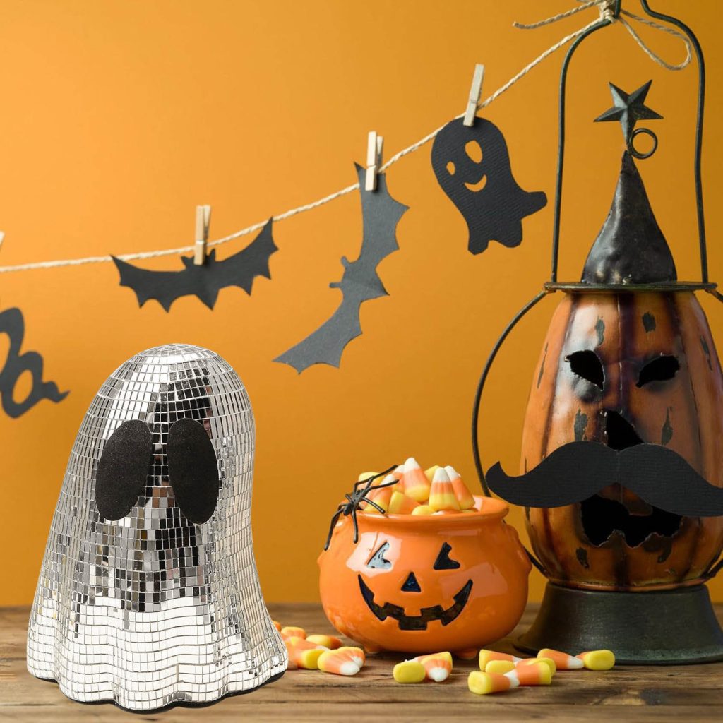 Silver mirrored ghost ornament with black eyes among Halloween decorations