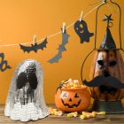 Silver mirrored ghost ornament with black eyes among Halloween decorations
