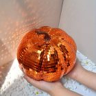 Orange mirrored pumpkin with square tiles and curled stem in hand