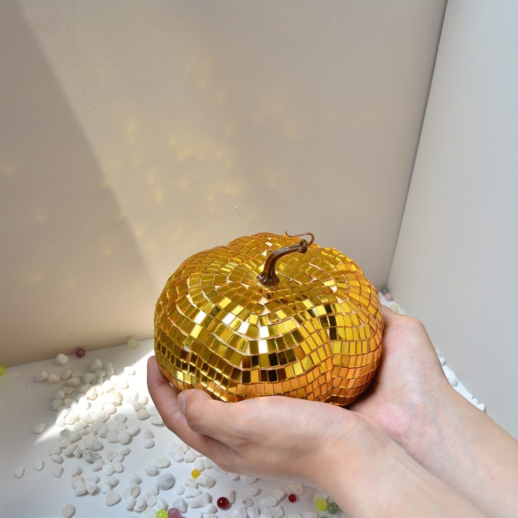 Gold mirrored pumpkin with dark curled stem in hand