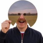 Person holding a reflective face prop in front of their face