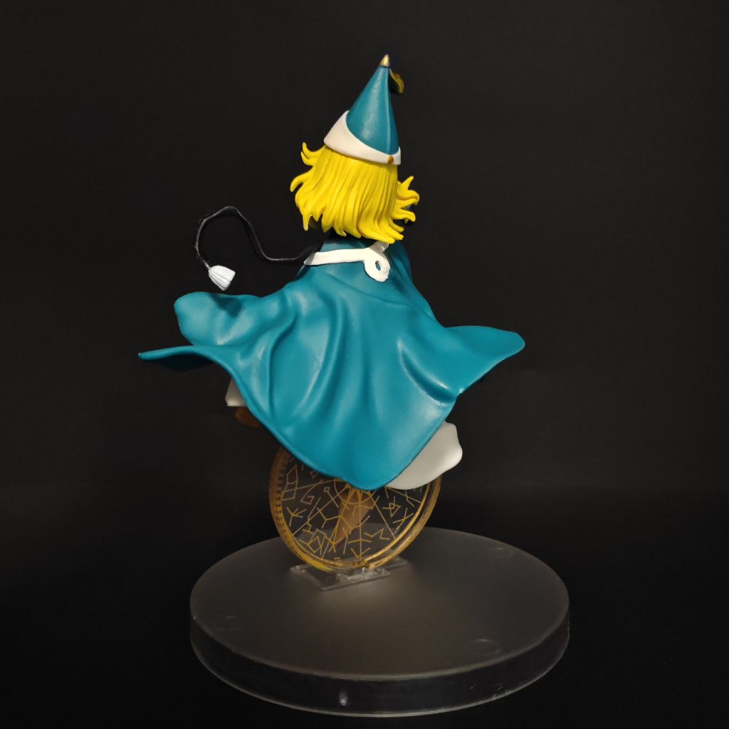 Full back view of Coco figurine with teal cape and gold-patterned display motif