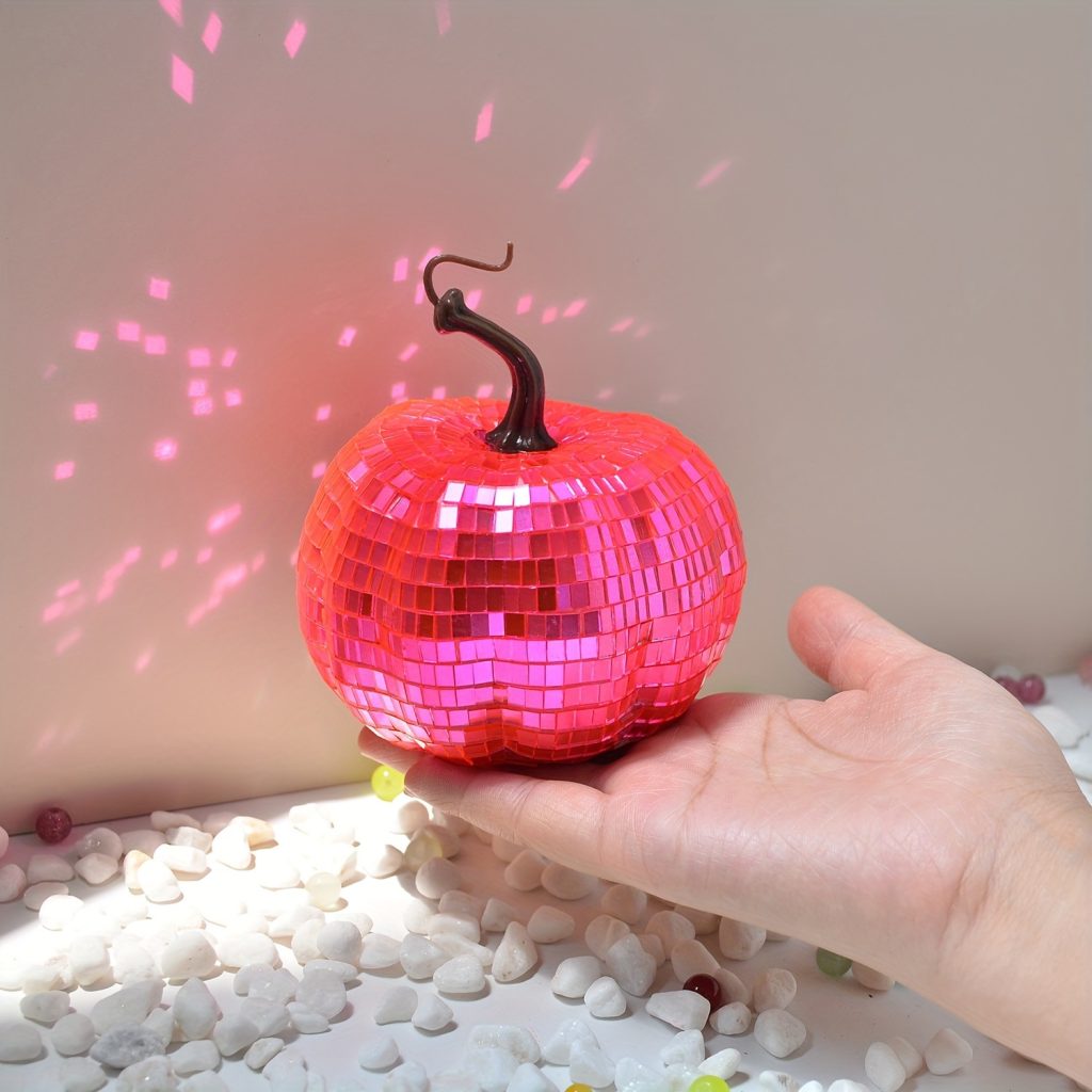 Pink tile-covered pumpkin reflecting light in hand