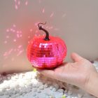 Pink tile-covered pumpkin reflecting light in hand