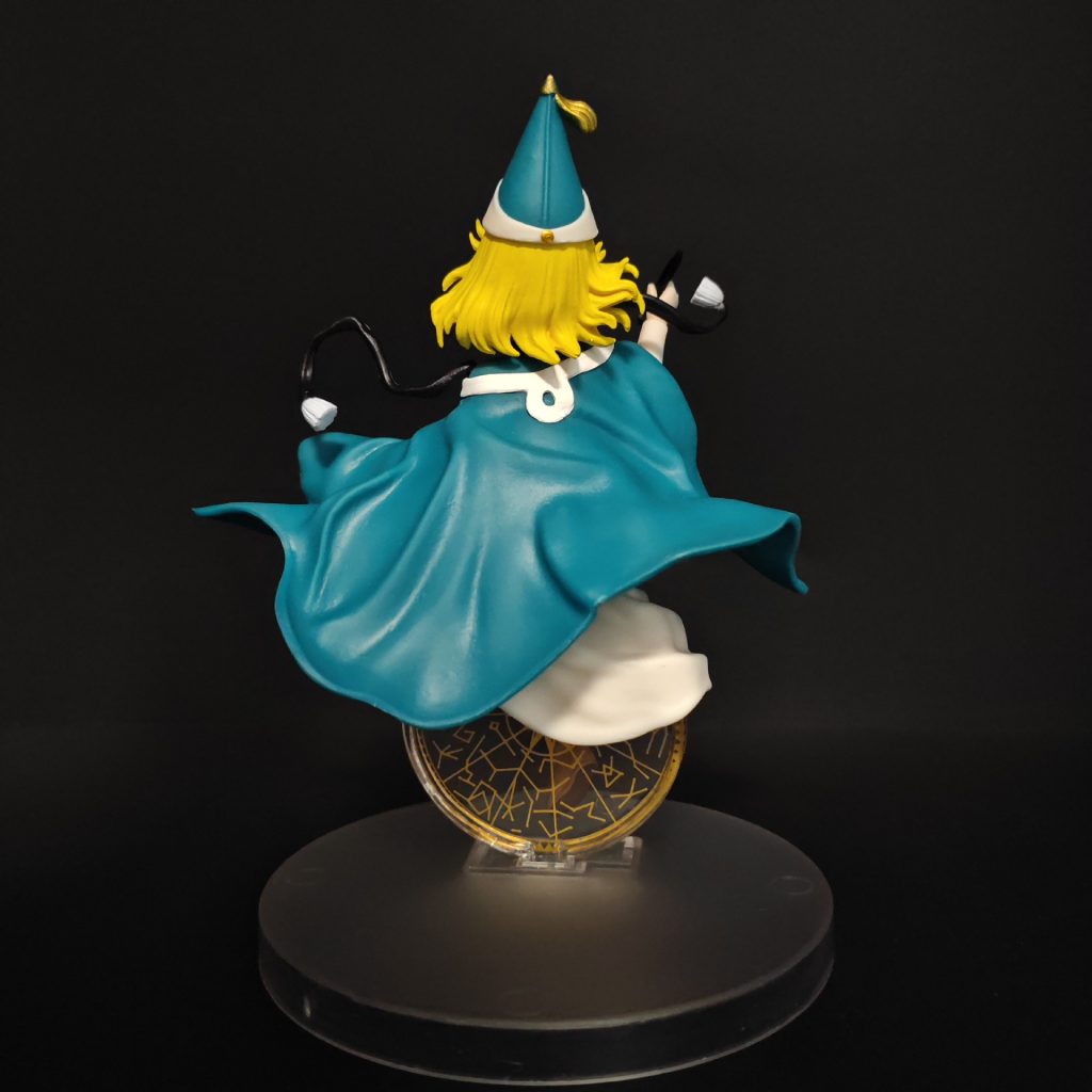 Rear view of Coco figurine showing swept teal cape, blonde hair and display base