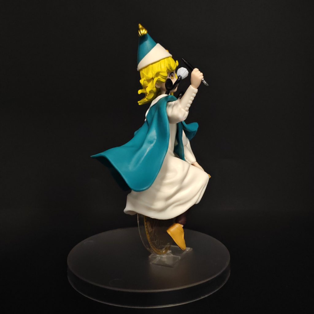 Opposite rear-side angle of Coco figure with sweeping cape and drawing pen