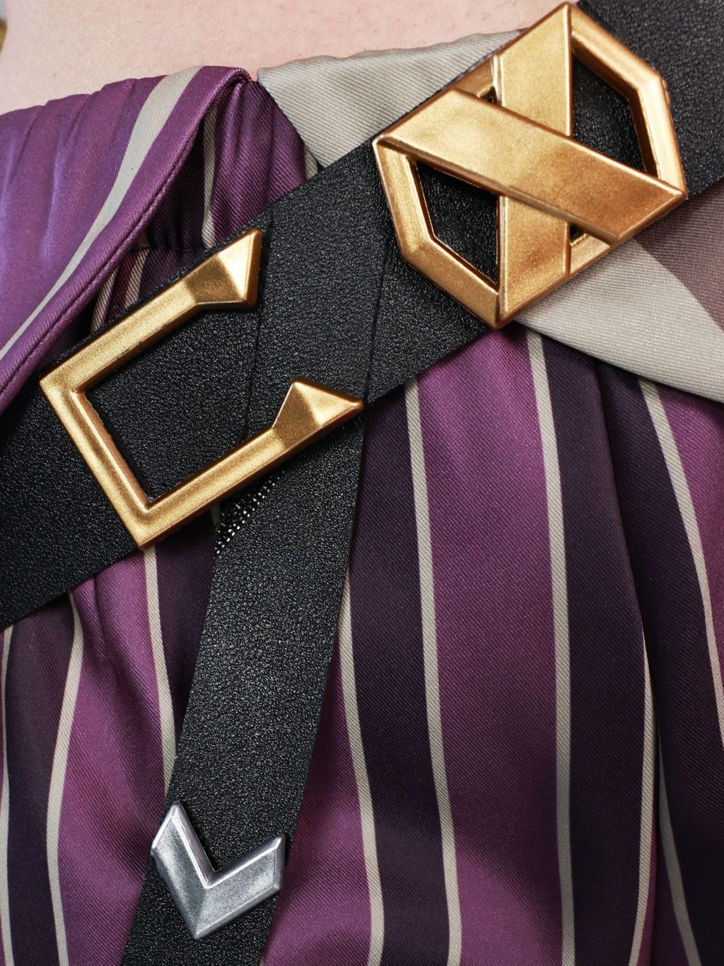 Angular gold buckle over purple-striped costume fabric