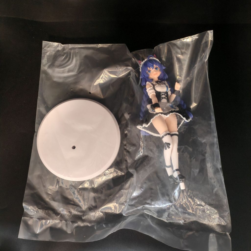 Standing figurine and round white base in clear bag packaging