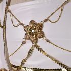 Mira floral chest ornament with a clear center accent and gold-tone draped chains over the white bandeau