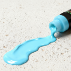 Cyan acrylic paint flowing from the open bottle
