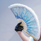 Photographed blue-and-white folding fan open in a black gloved hand