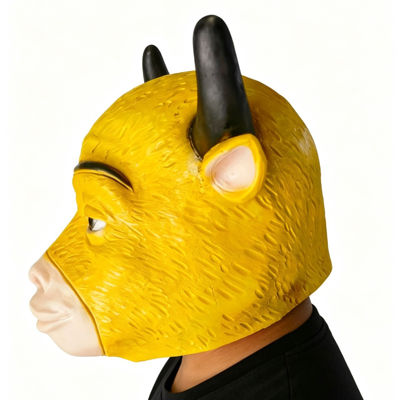 Side view of a yellow bull mask being worn, showing black horns, a pointed ear and a pale muzzle