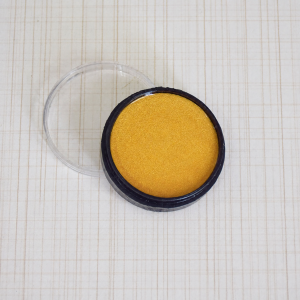 Gold metallic cosmetic paint in a round pot with clear lid