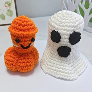 Crochet orange Halloween novelty figure beside its white ghost cover