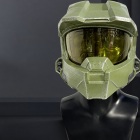Olive-green Master Chief cosplay helmet with gold visor on a display bust