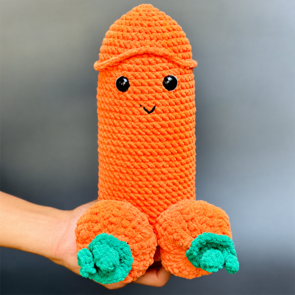 Hand holding uncovered orange crochet Halloween figure with green pumpkin stem accents