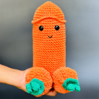 Hand holding uncovered orange crochet Halloween figure with green pumpkin stem accents