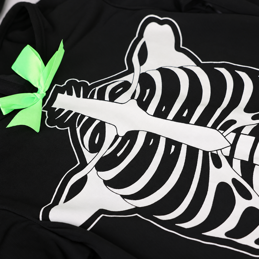 Close-up of white ribcage graphic and green neck bow on black costume