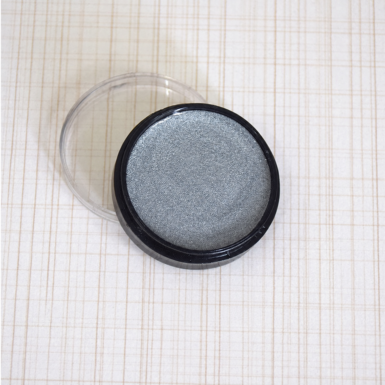 Silver metallic cosmetic paint in a round pot with clear lid