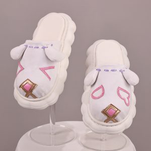 Pair of white cat-face slip-on shoes with pink and gold details