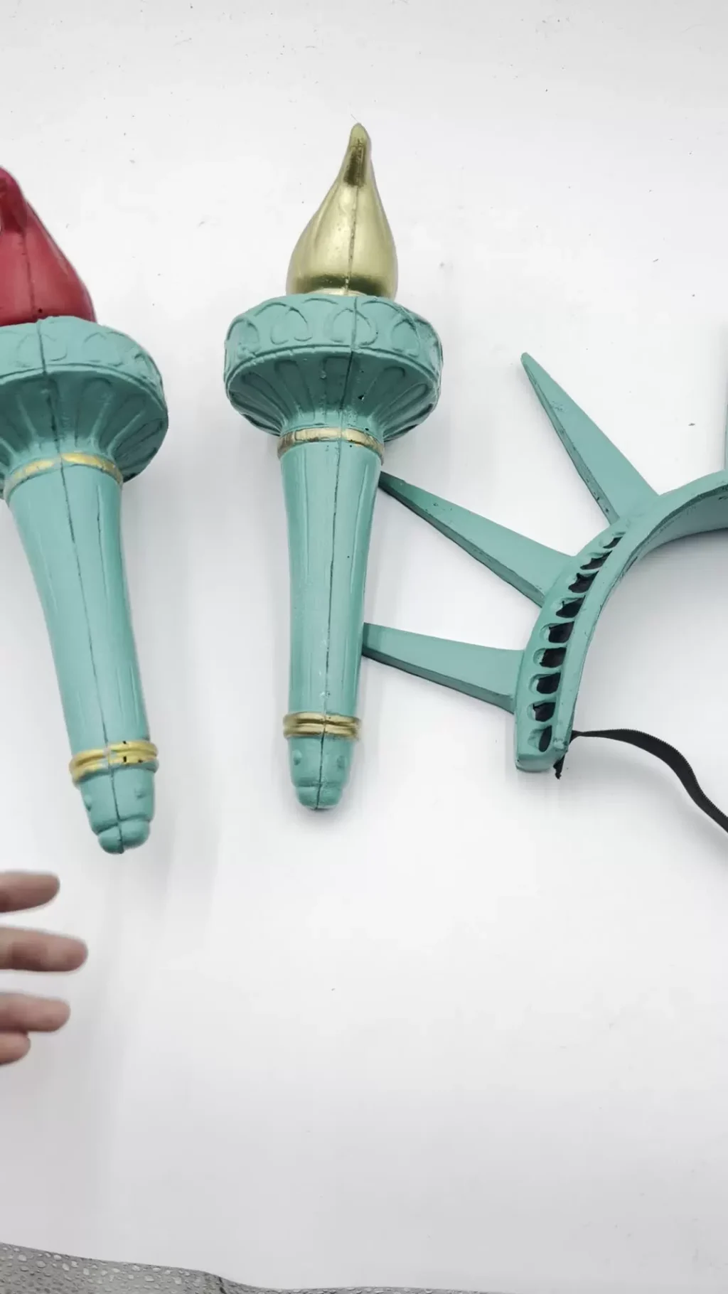 Close detail of red and gold torches beside seven-ray crown and elastic