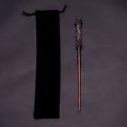 Reddish wand with rough dark handle beside black pouch