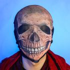 Printed skull mesh head covering worn with red cape