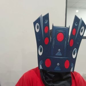 Speakerman printed head mask closeup with red and pale speaker circles